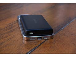 Die Baseus PicoGo AM52 MagSafe-Powerbank lädt ein Smartphone und liegt auf einem Tisch.