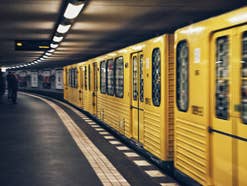 Eine gelbe Berliner U-Bahn fährt in einen Bahnhof ein.