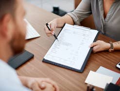 Person zeigt einer anderen einen Vertrag.