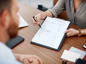 Person zeigt einer anderen einen Vertrag.