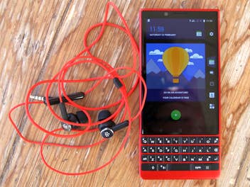 Das BlackBerry Key2 Red Edition und sein Headset auf einem Holztisch liegend.
