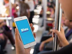 Ein Handy mit Blau-Logo auf dem Display wird in der U-Bahn genutzt
