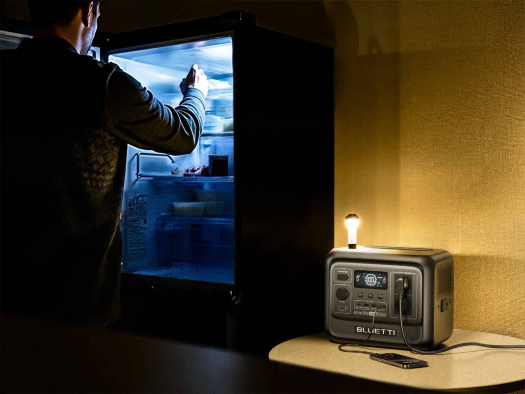 Mann steht vor einem offenen Kühlschrank. Daneben die Bluetti Elite 100 V2, die das Licht mit Strom versorgt.