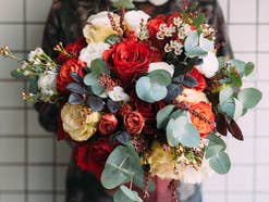 Eine Person hält einen großen Blumenstrauß mit Eukalyptusblättern drin.