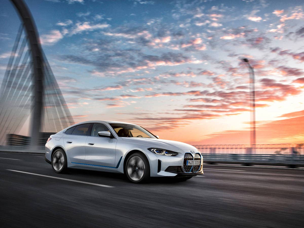 BMW i4 fährt auf einer Brücke im Sonnenaufgang