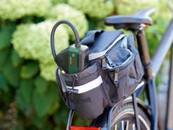 Eine elektrische Luftpumpe von Bosch steckt in einer Packtasche hinten auf einem Fahhrad