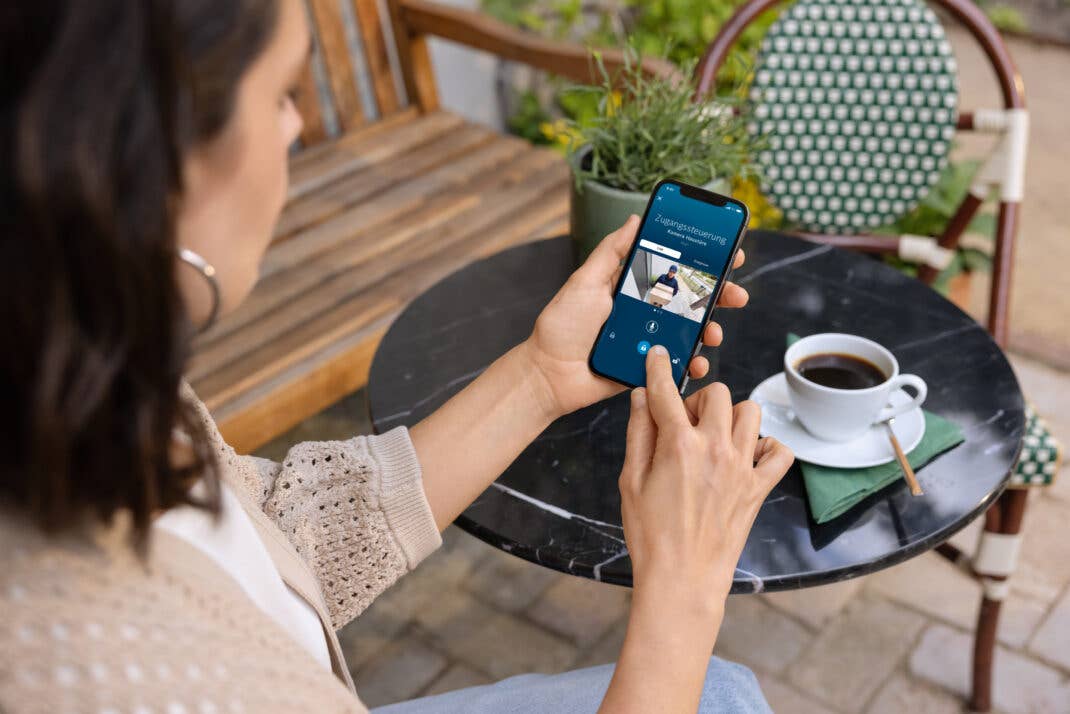 Bosch Smart Lock auf einem Handy, das eine Frau in der Hand hält.