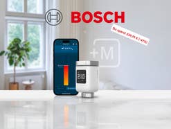 Bosch Smartes Heizkörper Thermostat II mit einem Smartphone das einen Temperaturregler zeigt stehen auf einem weißen Tisch in einem modernen Wohnzimmer. Darüber ist das Logo von Bosch zu erkennen.