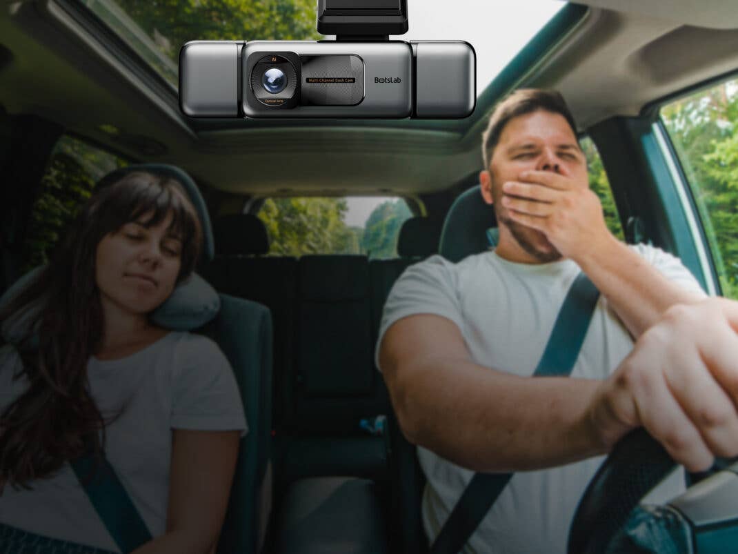 Zwei Personen sitzen im Auto. Eine schläft, die andere gähnt. Im Fokus steht die Botslab G980H 4-Kanal-Dashcam deren Linse man sieht.