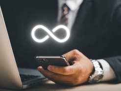 Business-Mann hält ein Smartphone darüber das Unendlichkeitssymbol