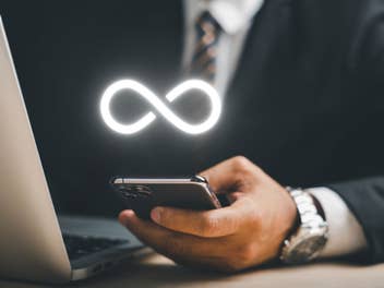 Business-Mann hält ein Smartphone darüber das Unendlichkeitssymbol