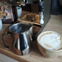 Die Milch ist sehr schnell aufgeschäumt, nur eignet sie sich kaum für Latte Art. Milchkännchen, Kaffeetasse und Milch an der Dampflanze der Krups Coffee Crush