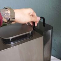 Über einen Schwenkgriff kann man den Wassertank herausheben. Hand hebt Wassertank von Krups Coffee Crush Kaffeemaschine an