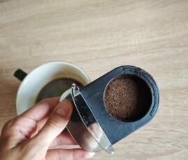 Der Kaffee-Puck ist zwar gleichmäßig getamped, aber der Mahlgrad ist sichlich zu grob für Espresso. Hand hält Behälter mit Kaffee-Satz aus der Krups Coffee Crush
