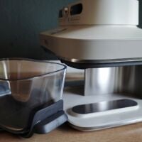 Der Trennsteg rundet nach hinten und verdeckt die halbe Rückseite. Am Boden befindet sich die Schiene zum Halt der Glasbehälter. Ninja Crispi DualZone schräg von der Seite mit Glasbehälter daneben