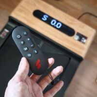 Eine handliche Fernbedienung für ein eher unhandliches Gerät. Hand hält Fernbedienung über Walking Pad