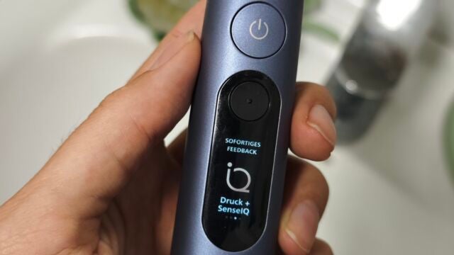 Echtzeit-Feedback Hand hält Philips Sonicare Next-Generation DiamondClean 9900 Prestige über dem Waschbecken