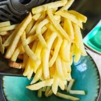 Pommes fallen aus Aifryer-Garkorb in Schüssel