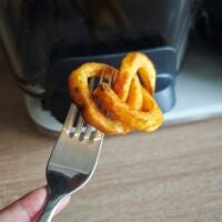 Knsuprige Pommes aus dem Airfryer Twister-Pommes auf einer Gabel