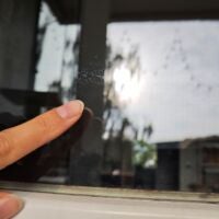Finger zeigt auf Wasserflecken auf Fensterscheibe