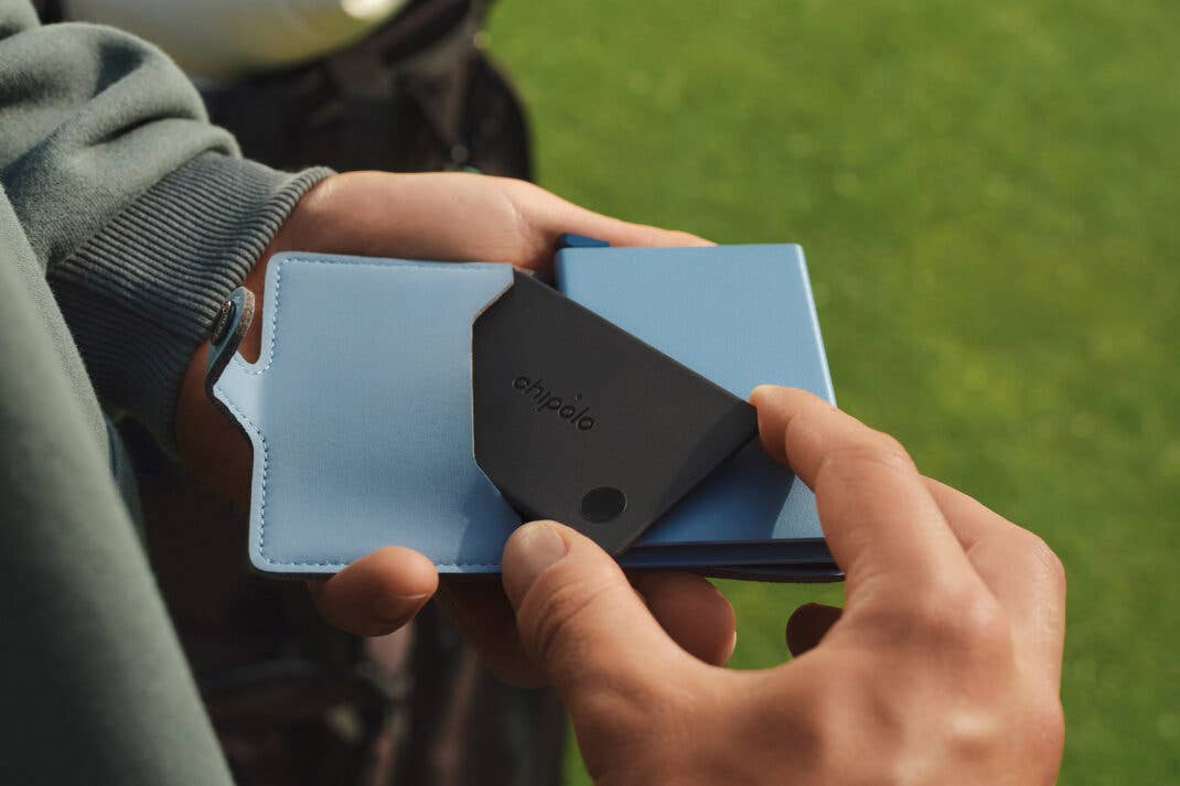 Eine Person hält einen Chipolo-Karten-Tracker in der Hand, neben einem Reisepass und Geldbörse.