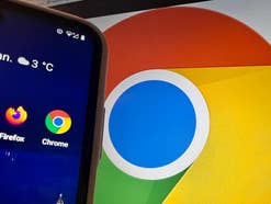 Chrome-App auf einem Smartphone mit Chrome-Logo auf einem Notebook-Monitor im Hintergrund.