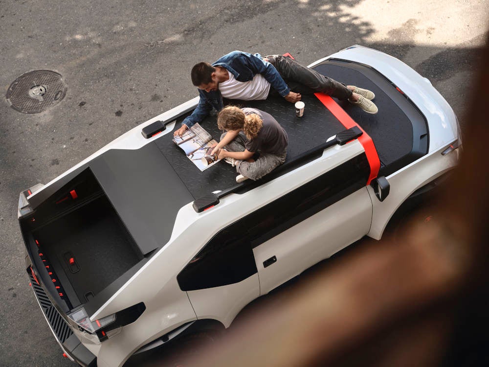 Zwei Personen sitzen und liegen auf dem Dach des Citroën Oli.