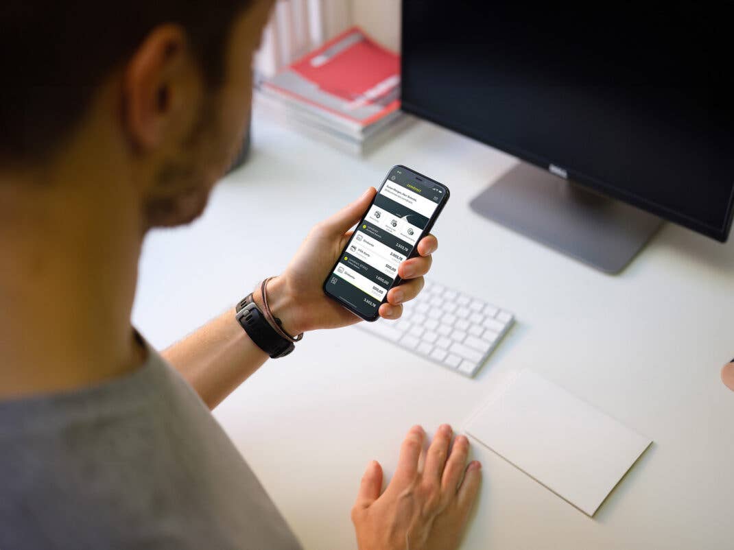 Person hält iPhone 11 in der Hand und schaut auf die comdirect-App.