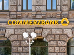 Der Commerzbank-Schriftzug an einer historischen Fassade, im Vordergrund Straßenlaternen