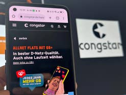 Smartphone mit Congstar-Homepage auf Bildschirm vor Congstar-Logo im Hintergrund.