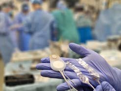 Eine Hand in einem chirurgischen Handschuh hält das Brain Interchange System von CorTec in einer medizinischen Umgebung.