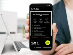 Person hält ein Handy in der Hand auf dem ein Angebot von Crash zu sehen ist.