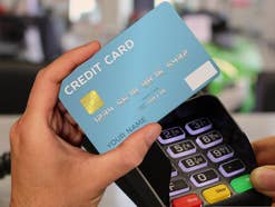 Eine Kreditkarte wird vor ein Bezahlterminal gehalten