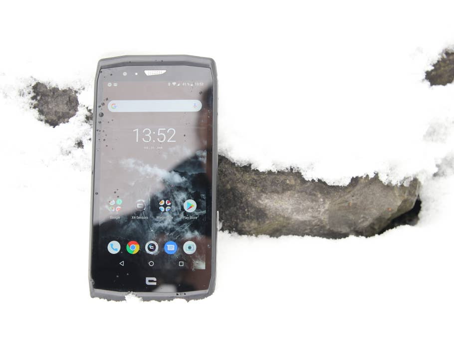 Das Crosscall Trekker-X4 im Schnee angelehnt an einen Stein