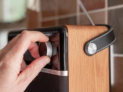 Ein DAB+Radio, an dem eine Hand den Sender einstellt
