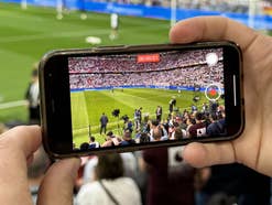 Ein Smartphone filmt im Stadion ein Fußballspiel