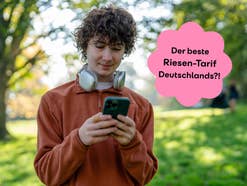 Person mit Smartphone steht in einem Park, daneben der Hinweis auf einen großen 5G-Tarif