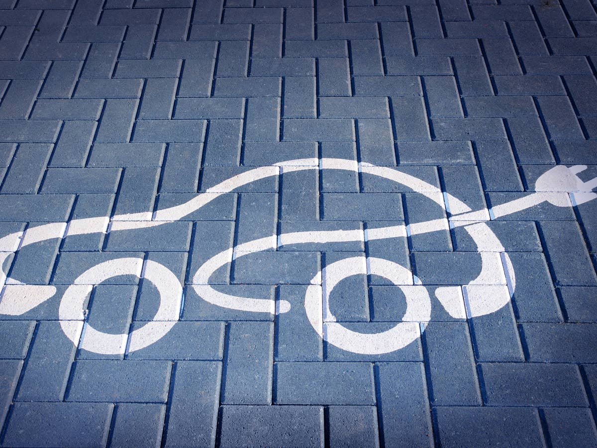 Symbol eines Elektroautos auf gepflastertem Weg.