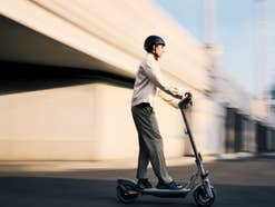 Ein Mann fährt auf einem E-Scooter über eine Straße