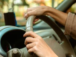 Während einer Autofahrt halten zwei Hände ein Lenkrad umschlossen