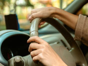 Während einer Autofahrt halten zwei Hände ein Lenkrad umschlossen