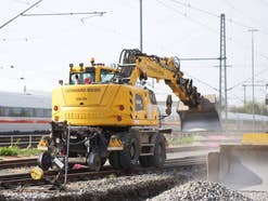 Bagger im Gleis vor einem ICE.