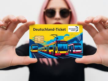 Deutschlandticket in den Händen einer blonden Frau mit Sonnenbrille.