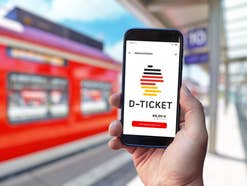 Deutschlandticket auf einem Smartphone vor einer Regionalbahn.