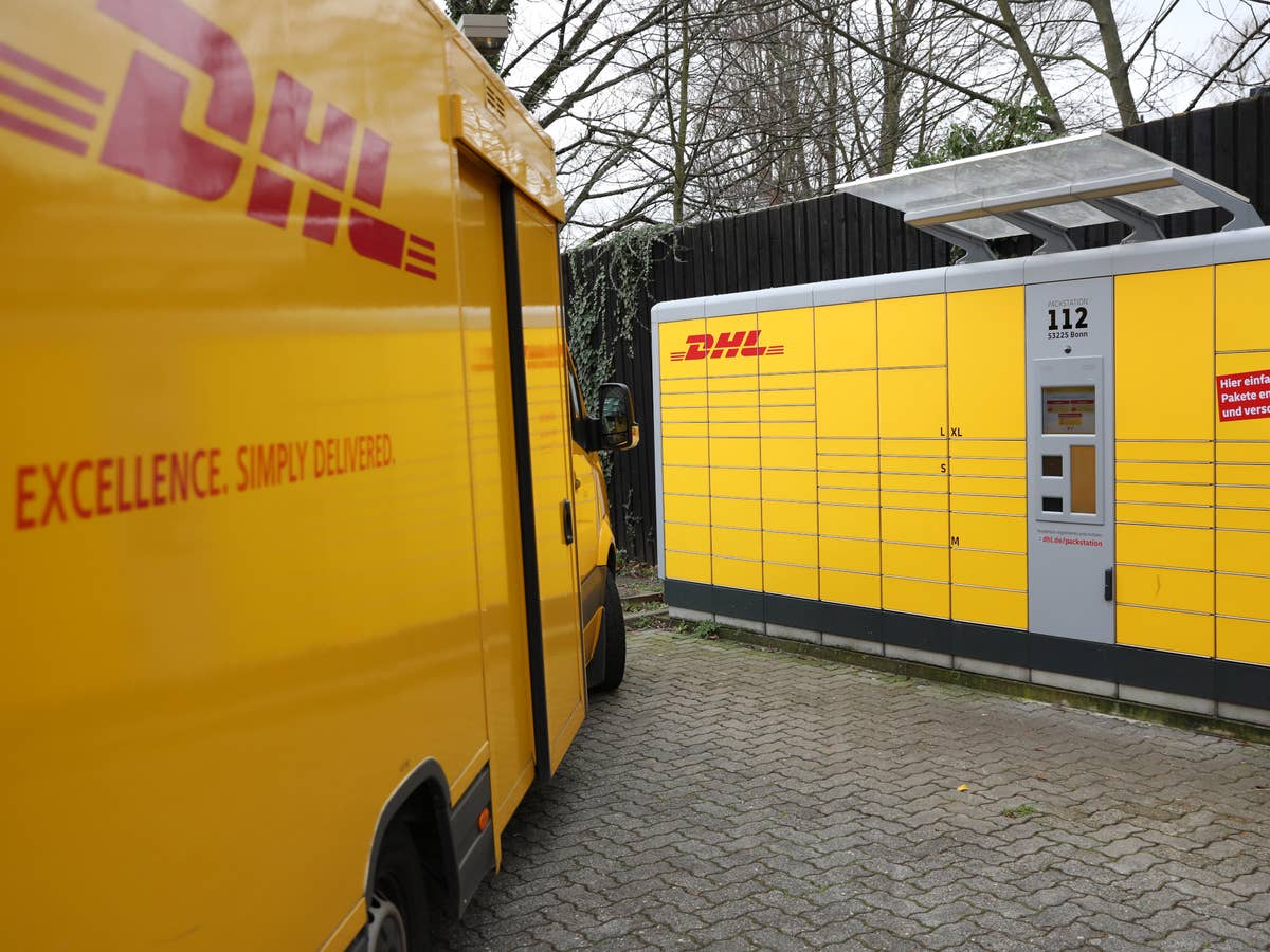 DHL-Lieferwagen steht vor einer Packstation.