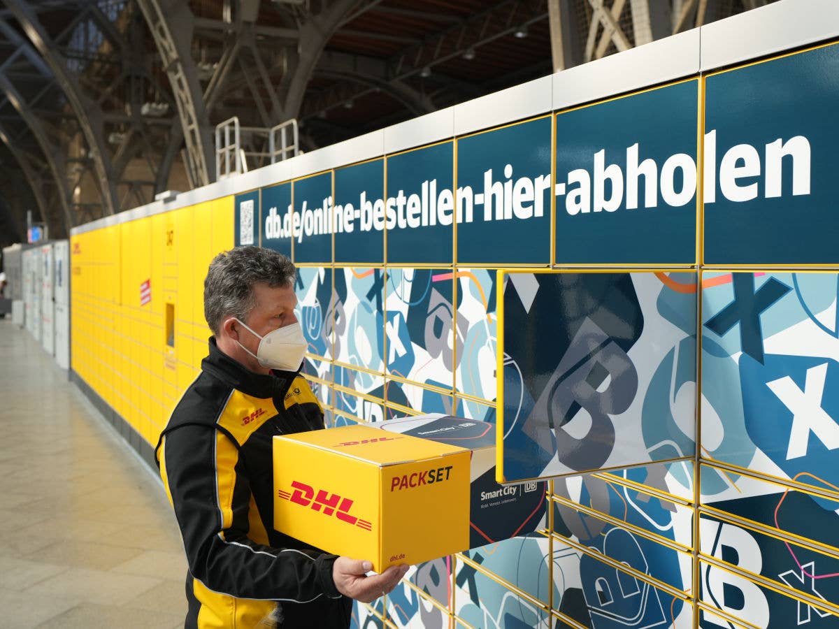 DHL-Zusteller legt Paket in eine DHL Packstation.