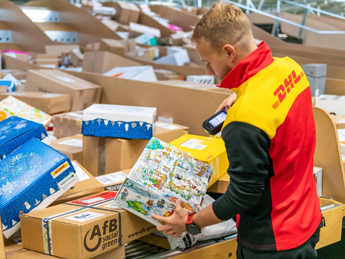 Ein DHL-Zusteller mit vielen Paketen