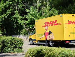 Ein DHL Zusteller vor seinem Fahrzeug