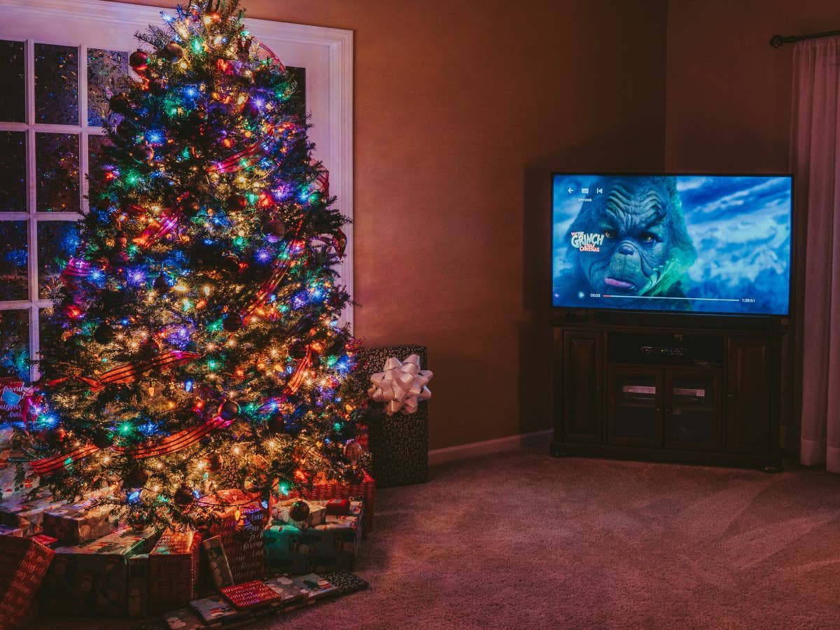 Ein Tannenbaum neben einem TV, auf dem ein Weihnachtsfilm läuft.