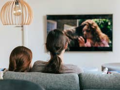 Zwei Frauen sitzen auf dem Sofa und gucken TV